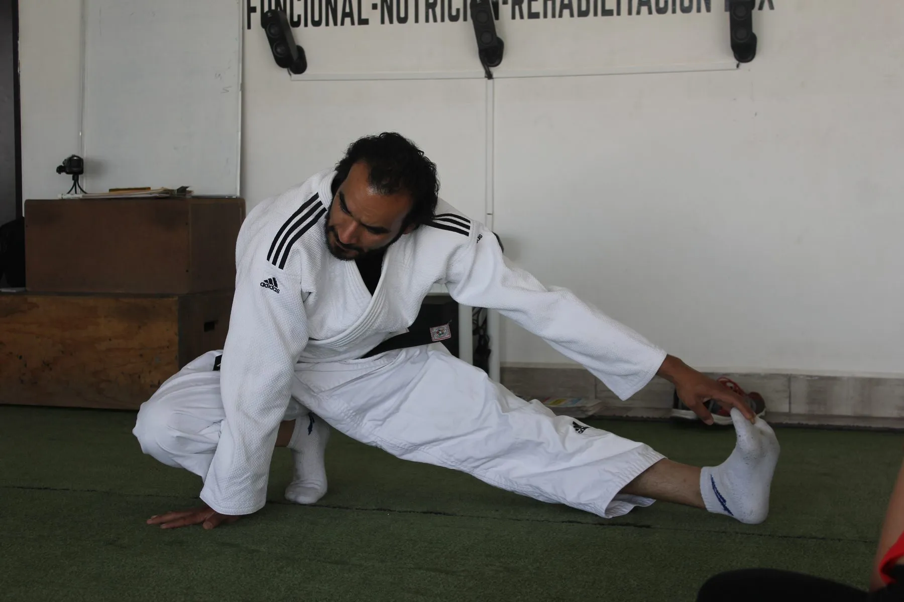 Instructor con judogi guiando un ejercicio de estiramiento